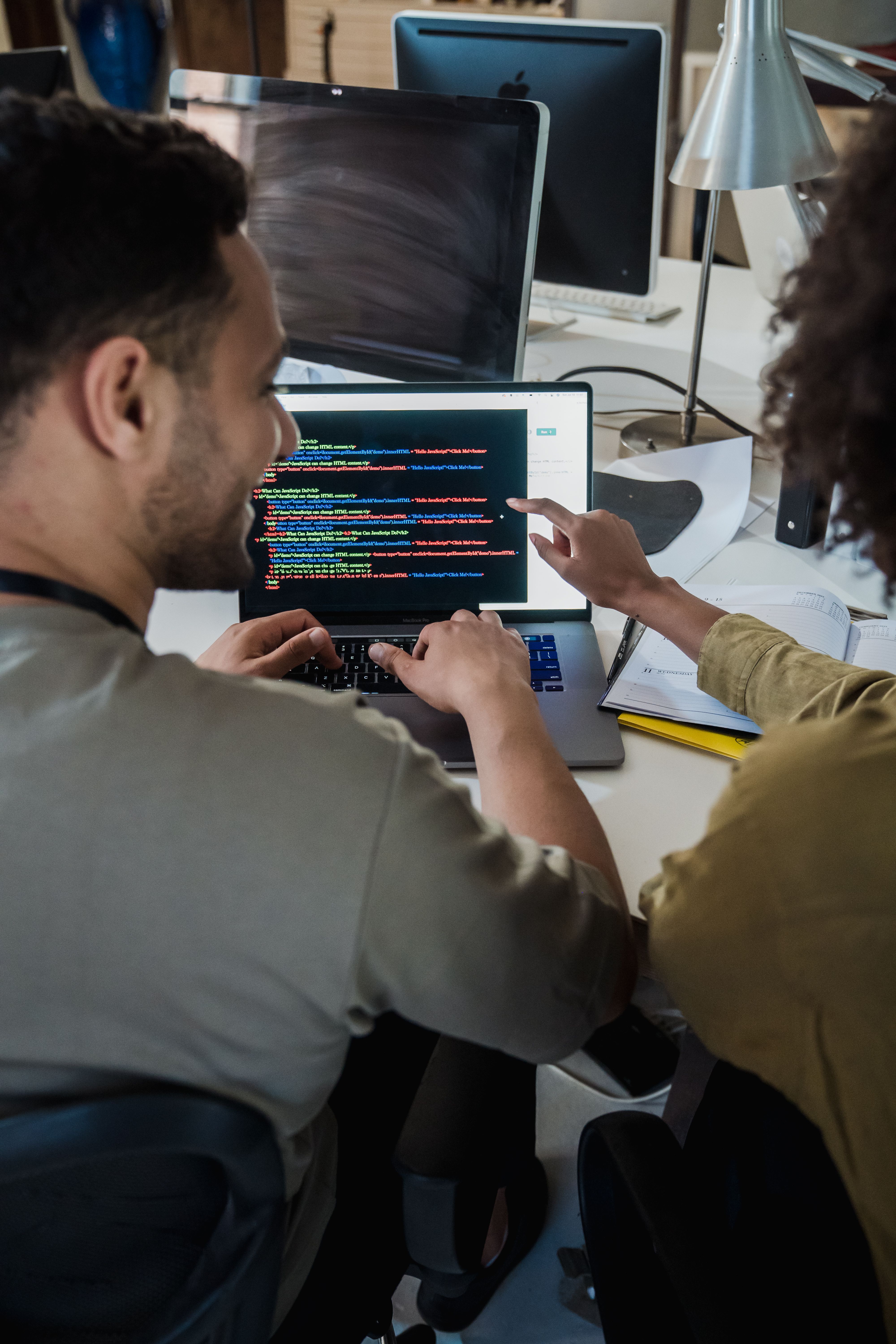 Two software developers reviewing code together on a laptop